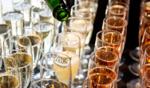 Champagne being poured into University of Guelph-branded glasses at a celebratory alumni event, with rows of filled glasses ready for guests.