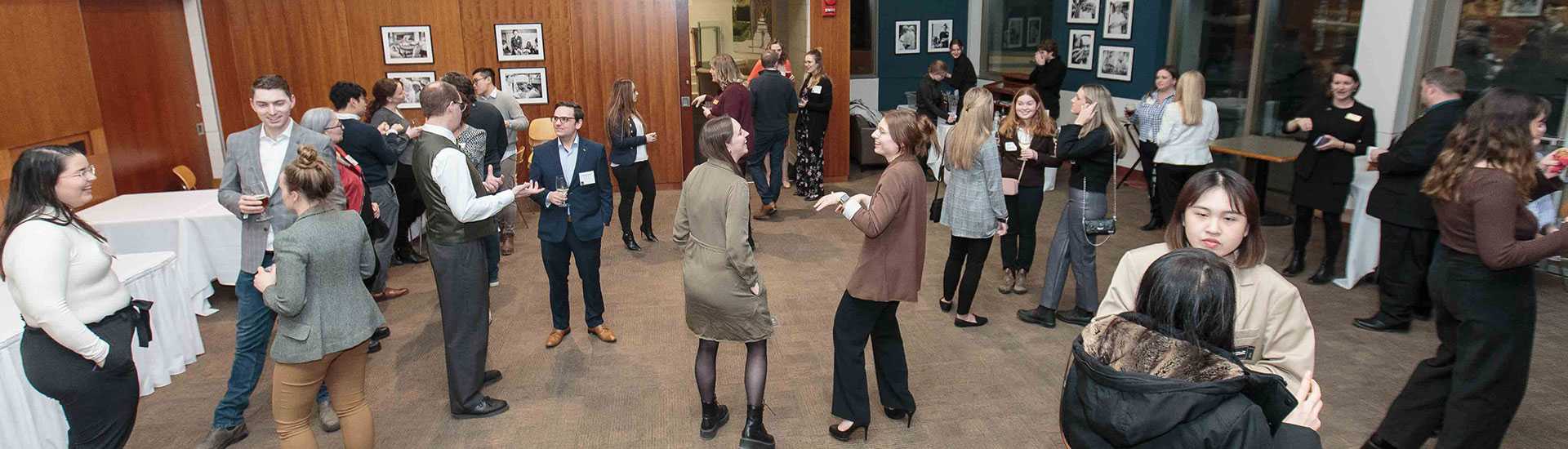 Attendees networking at the University of Guelph HAFA Career Night, with groups of people engaged in conversation in a warmly lit event space. 
