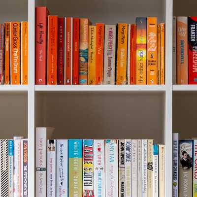 Color-coordinated bookshelves filled with books organized by spine color in a home library, creating a vibrant rainbow-like effect.