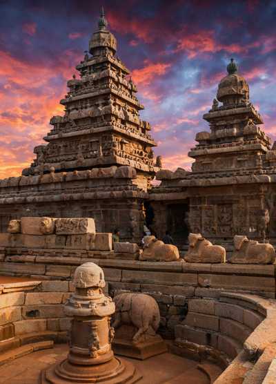 The ancient Shore Temple in Mahabalipuram, India, captured at sunset with its intricate stone carvings and towering structures highlighted against a dramatic sky.